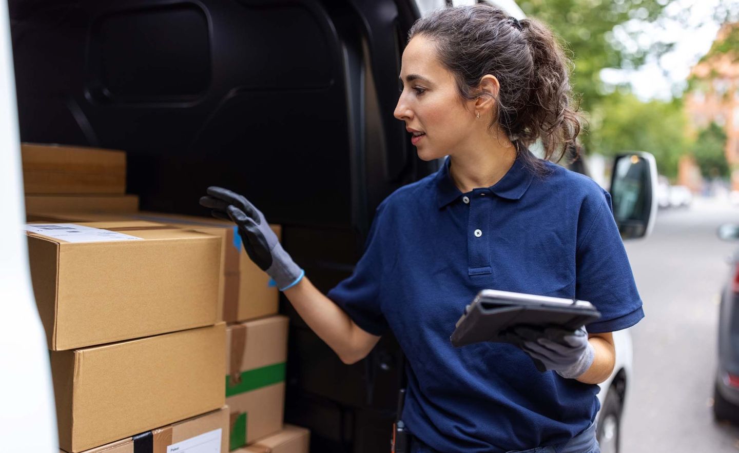 Paketbotin kontrolliert Pakete im Lieferauto
