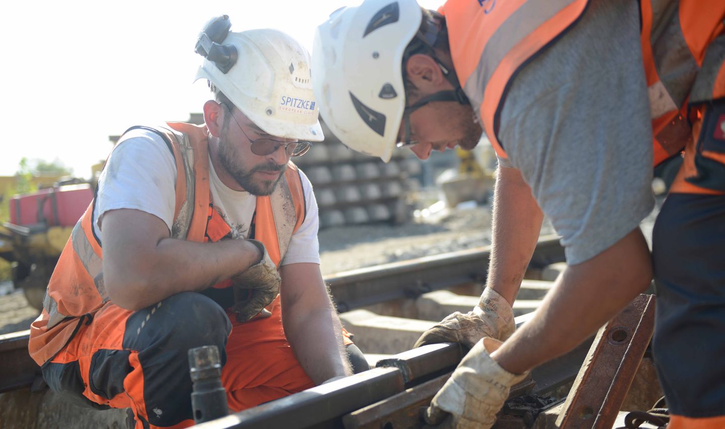Gleisbauer arbeiten an Bahnschienen.