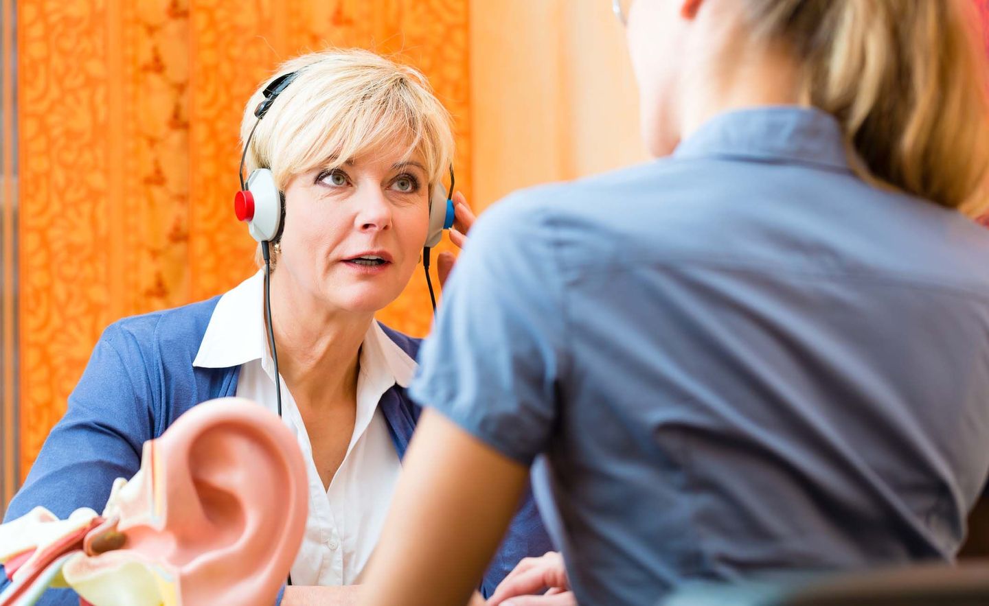 Hörakustikerin bei der Arbeit: Eine junge Frau macht einen Hörtest bei einer älteren Dame