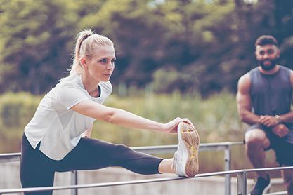 Fitnesstrainer und Sportlerin beim Dehnen.