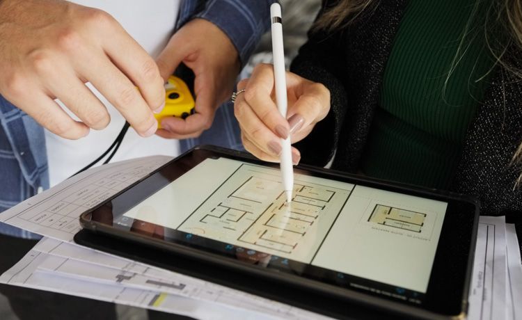 Zwei Bauzeichner arbeiten am Tablet an einem Bauplan.