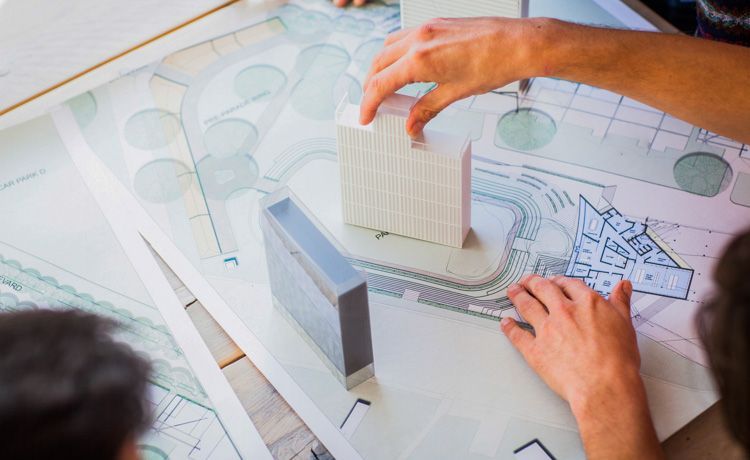 Die Hände eines Bauzeichners mit dem 3-D-Modell eines Hochauses