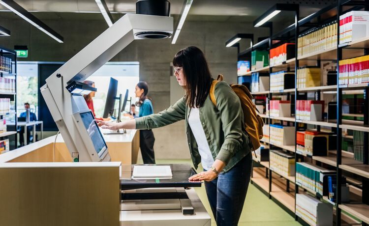 Duale Studentin BWL-Handel scannt ein Buch in der Bibliothek.