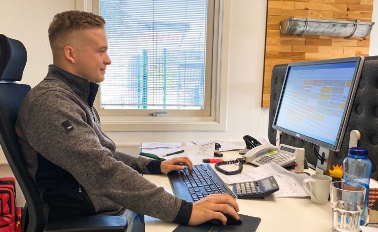 Azubi sitzt im Büro und arbeitet am PC.