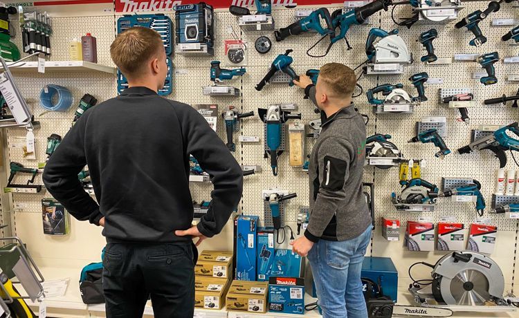 Verkäufer zeigt Kunden Arbeitsgeräte im Geschäft.