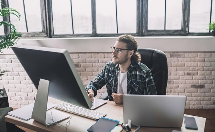 Informatiker mit Brille und Hemd sitzt an einem PC im Büro.