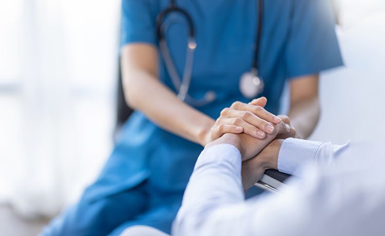 Krankenschwester hält Hand einer Patientin und leistet ihr emotionalen Beistand.