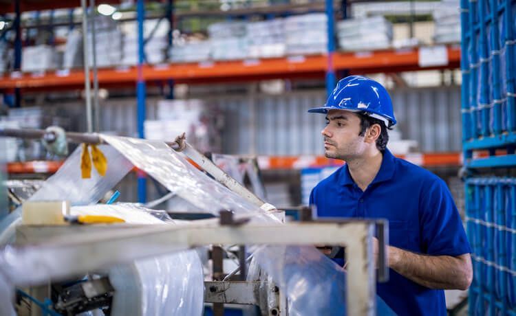 Junger Mann überwacht mit Schutzhelm Produktion.