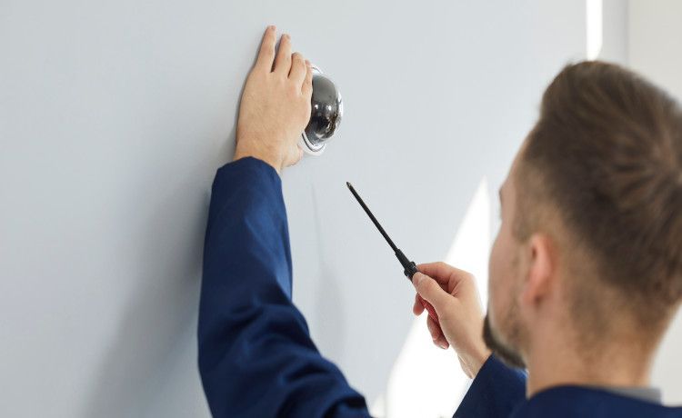 Fachkraft für Schutz und Sicherheit bringt Überwachungskamera an.