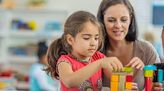 Frau spielt mit zwei Kindern mit Bauklötzen.