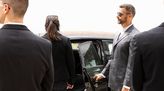 Personenschützer hält Schutzperson die Autotür auf.