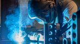 Schweißer trägt Schweißer-Maske und schweißt ein Metallteil.